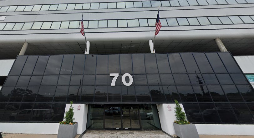 The entrance of 70 Sunrise Highway, a dark-glass office building with the number 70 above the doors.